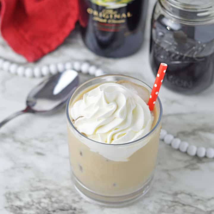 Baileys Iced Coffee in a glass with whipped cream and a red straw.