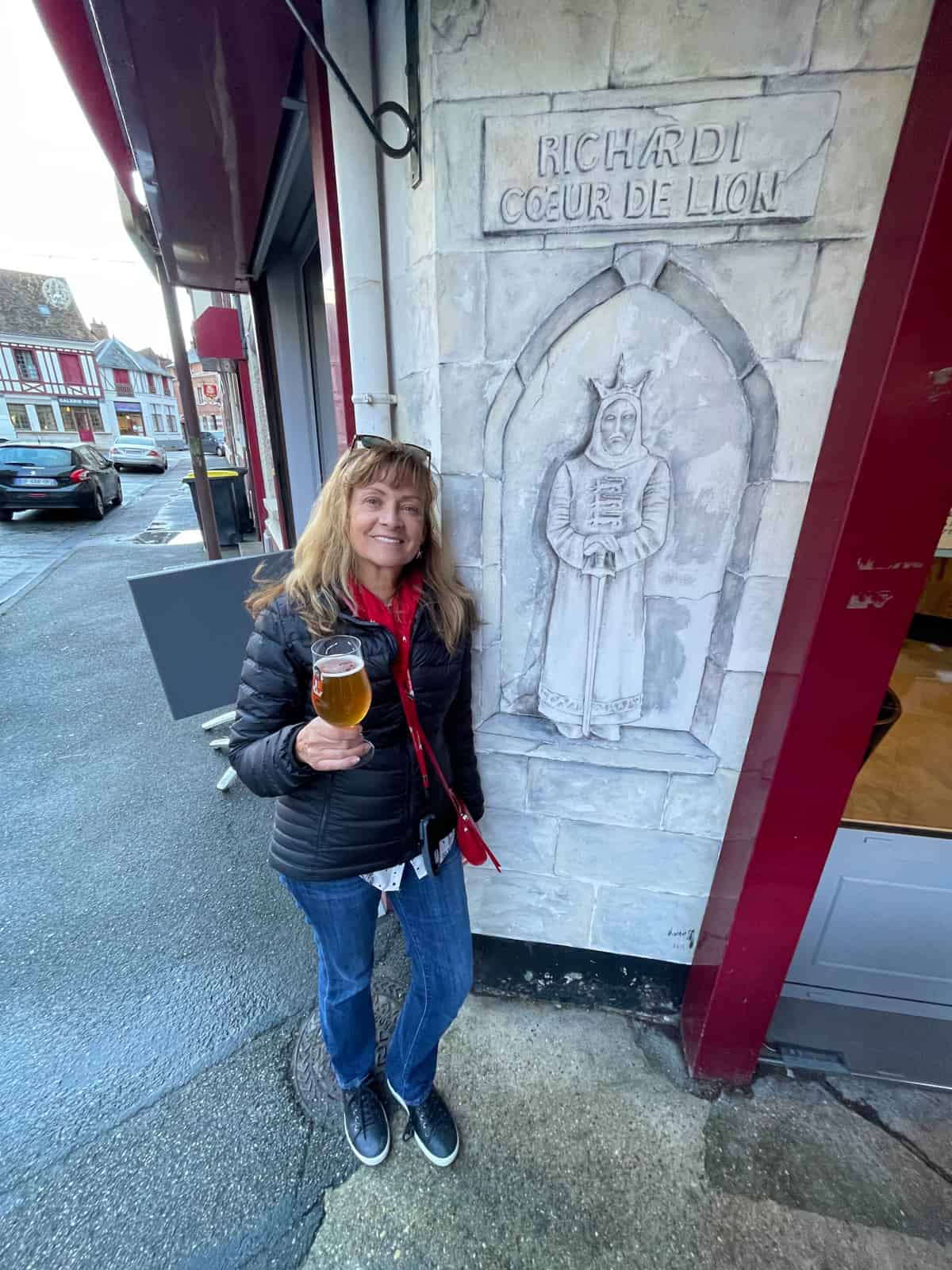 Woman standing in front of a pub with a beer.