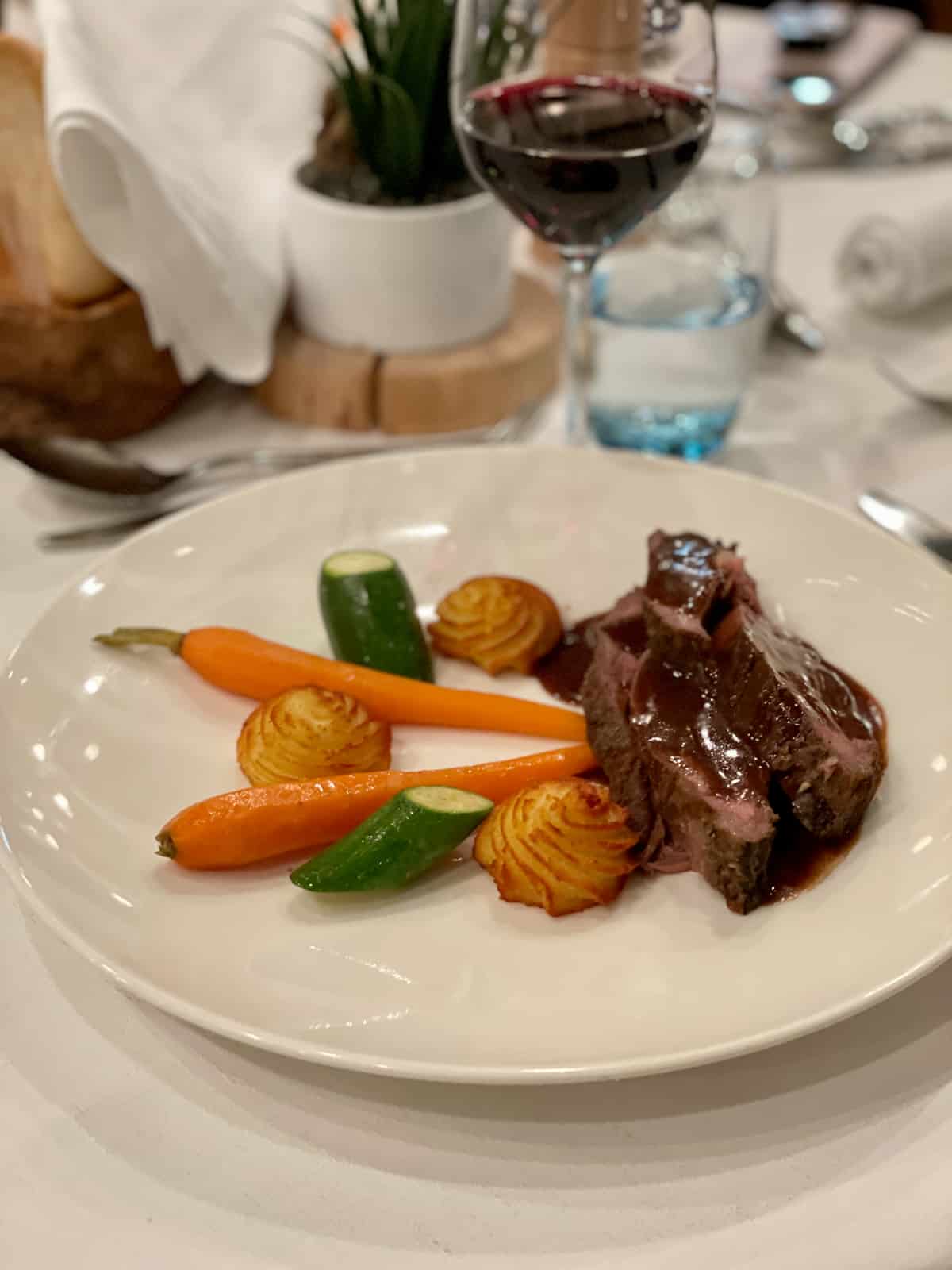 Beef and vegetables on a white plate.