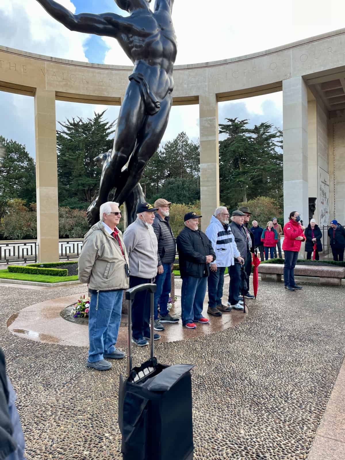 Veterans at Normandy in front of statue.