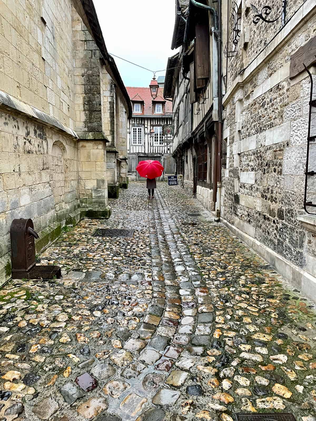 Narrow street with person with red umbrella.