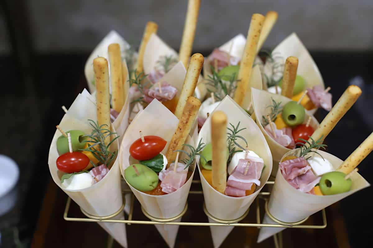 Cones filled with charcuterie foods in a rack.
