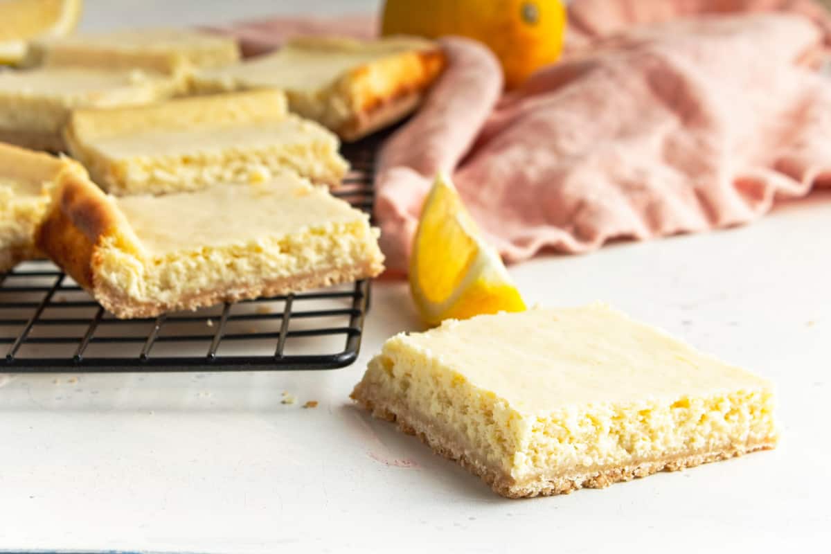 Lemon bars on wire rack with pink napkin.