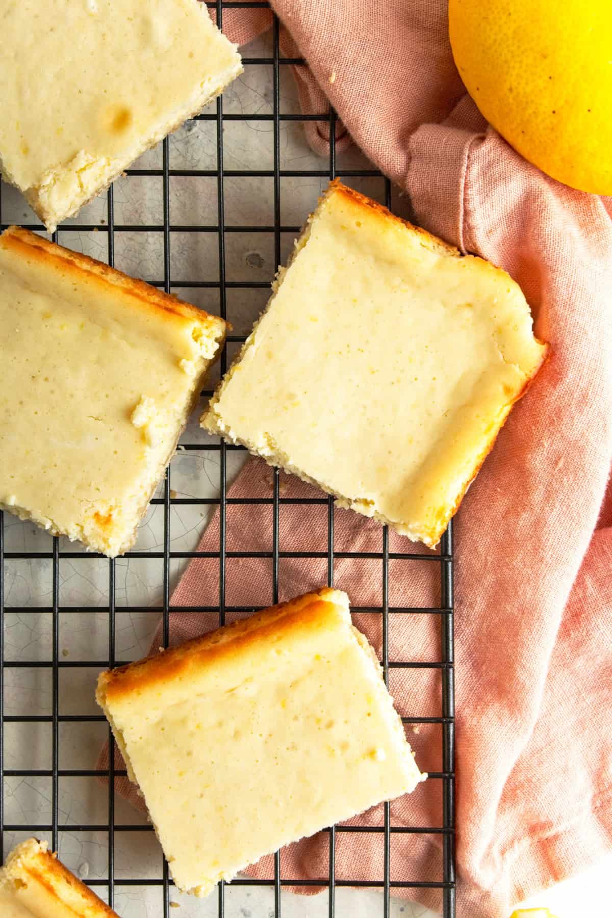 Lemon bars on wire rack with pink napkin.