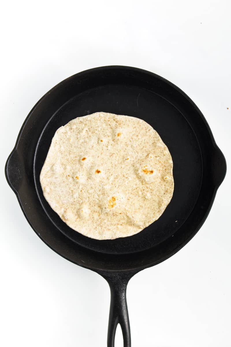 Tortilla cooking in a cast iron skillet.