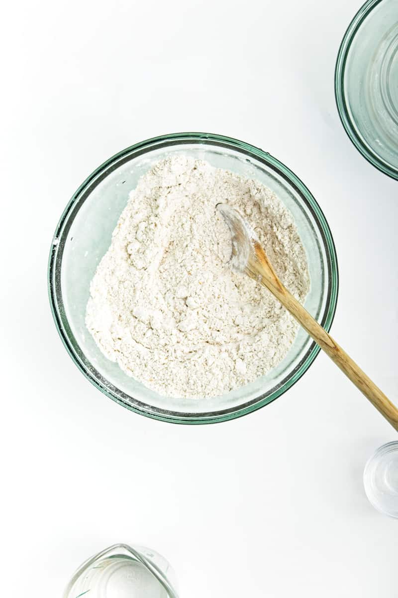 Flour and oil mixed in a glass bowl with a wooden spoon.