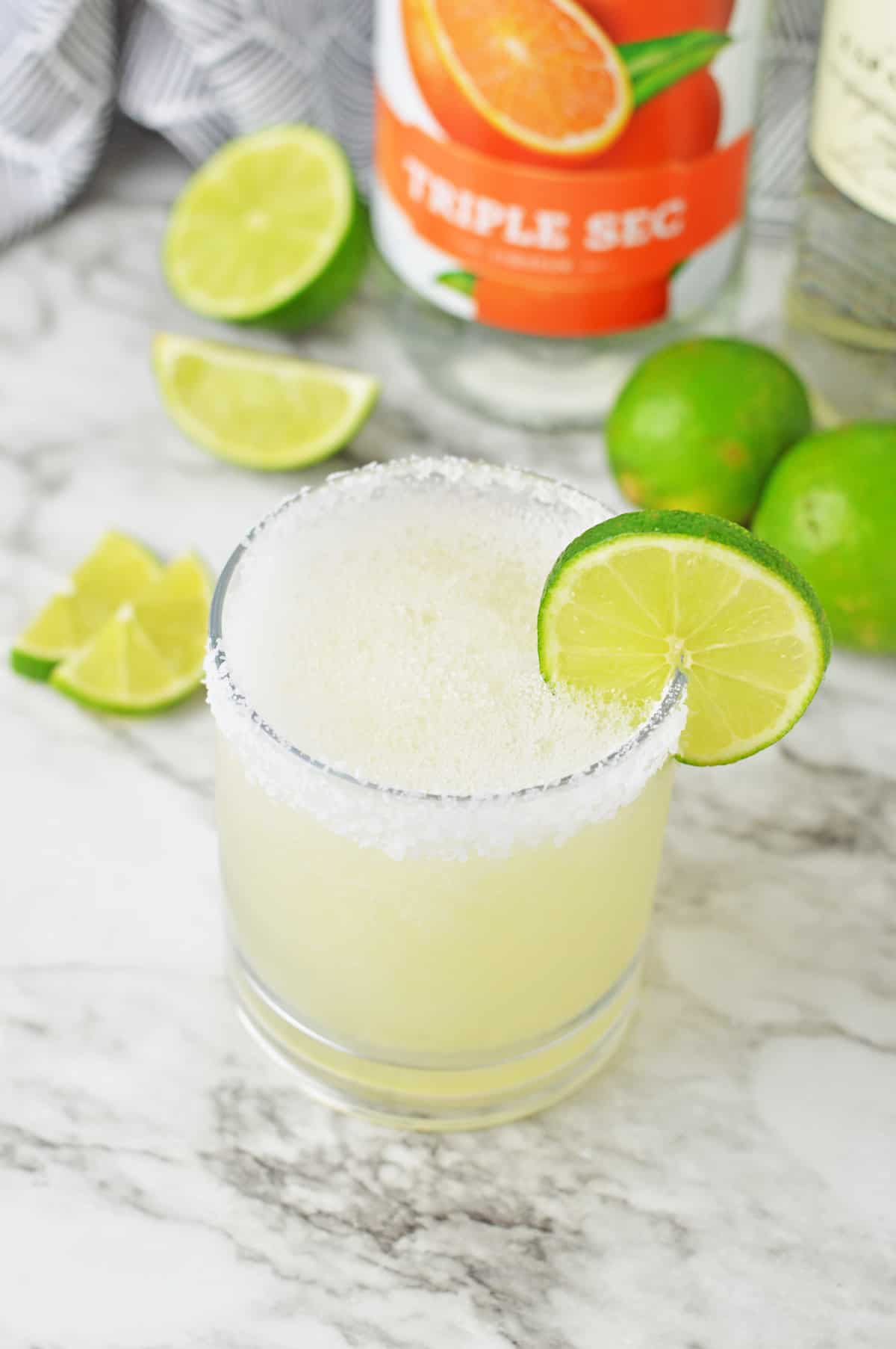 Frozen mezcal margarita on a white counter with limes.