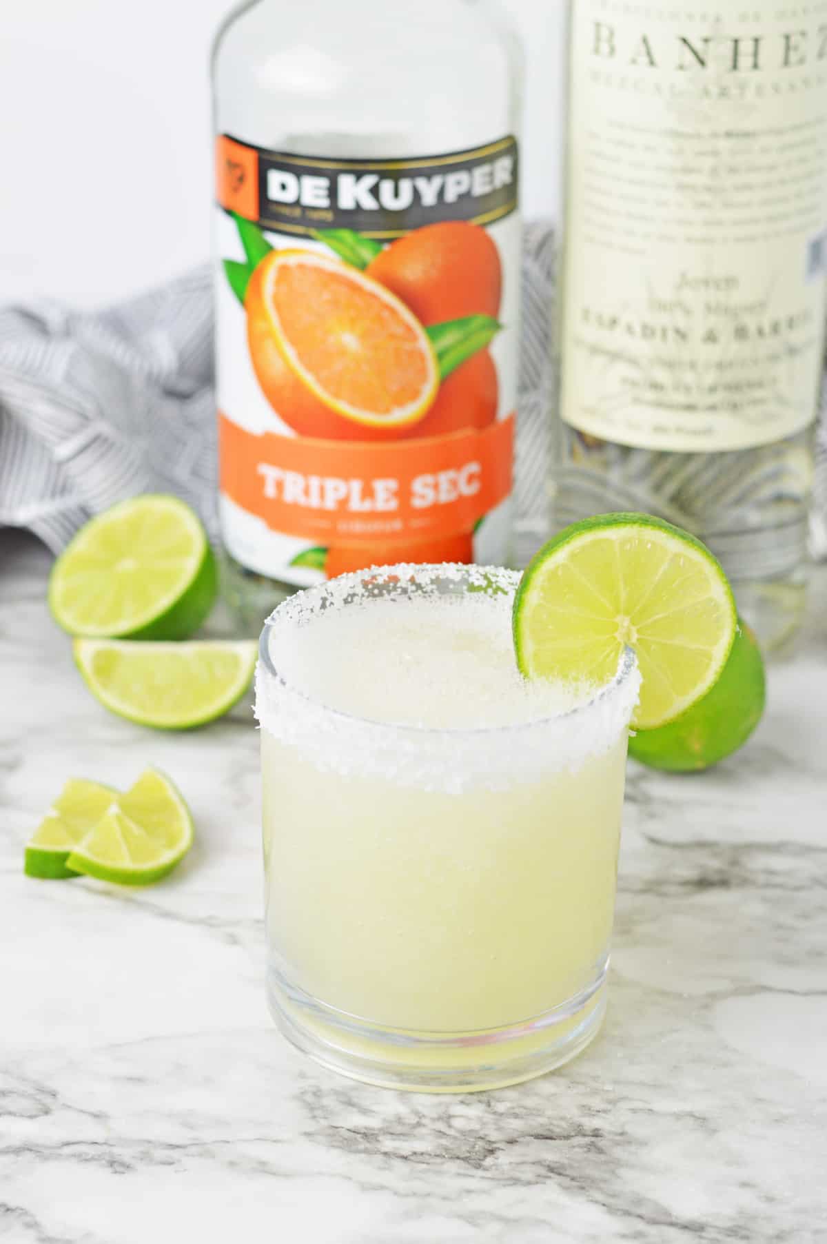 Frozen mezcal margarita on a white counter with limes.