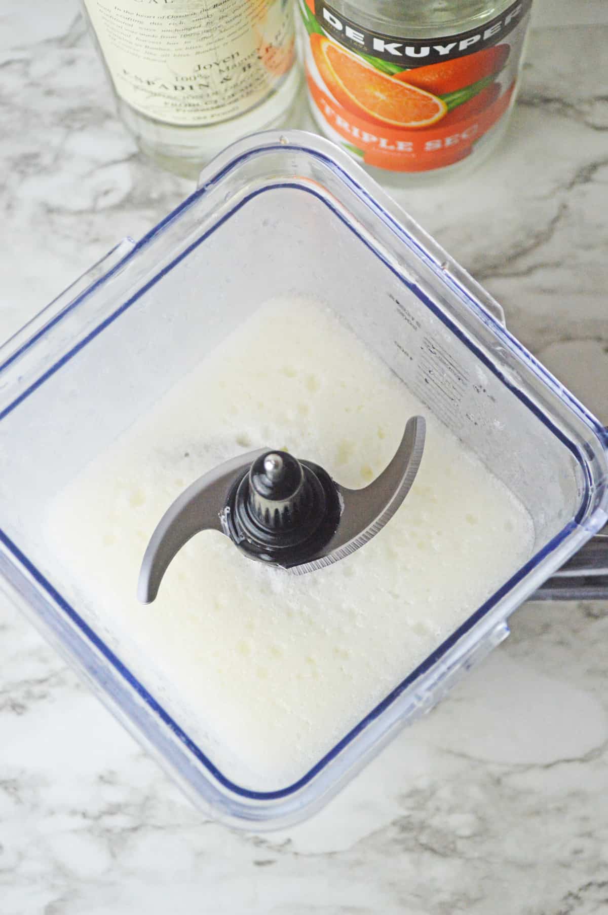 Ingredients for Frozen mezcal margarita in a blender on a white counter.