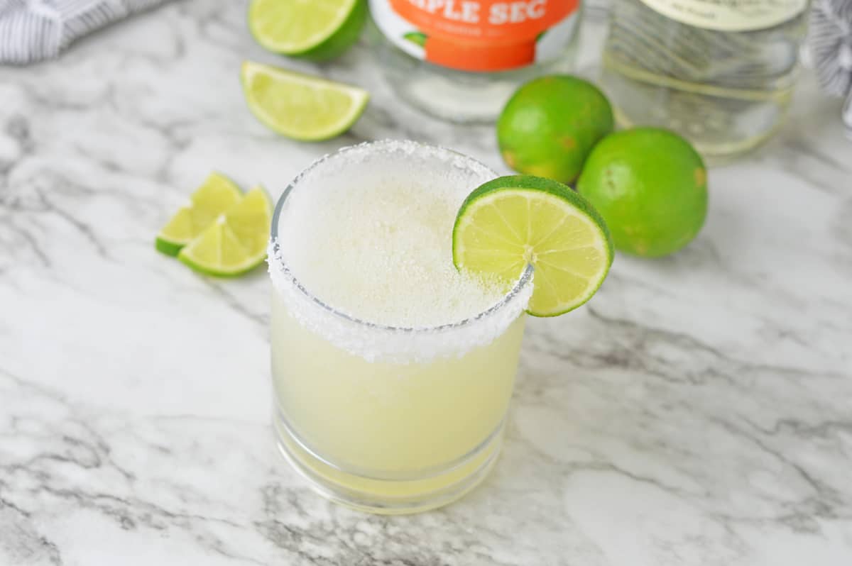 Frozen mezcal margarita on a white counter with limes.