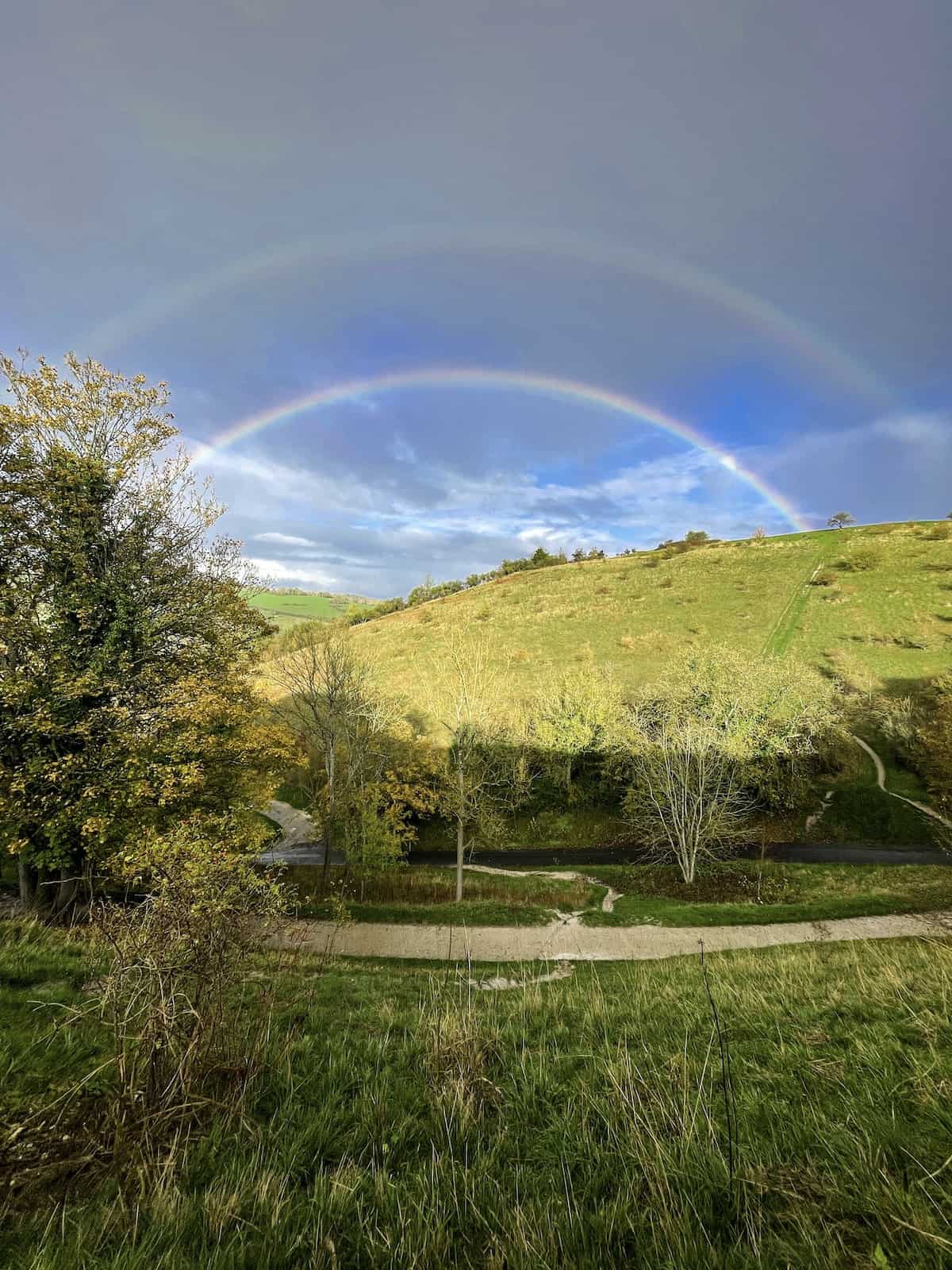Double rainbow over a hill.
