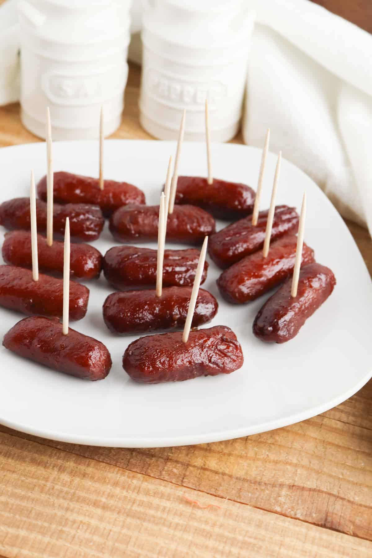 Little sausages with toothpicks on a white plate.