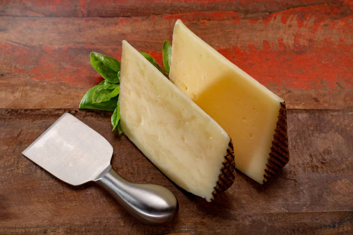 Manchego cheese on wood table with cheese knife.