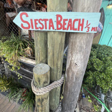 Siesta Beach sign on pole.