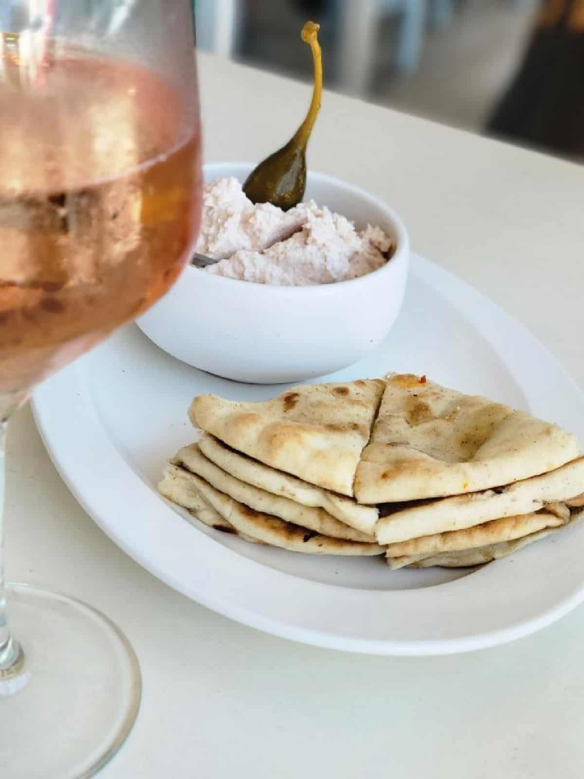 Fish dip with caperberry, pita bread, glass of wine.