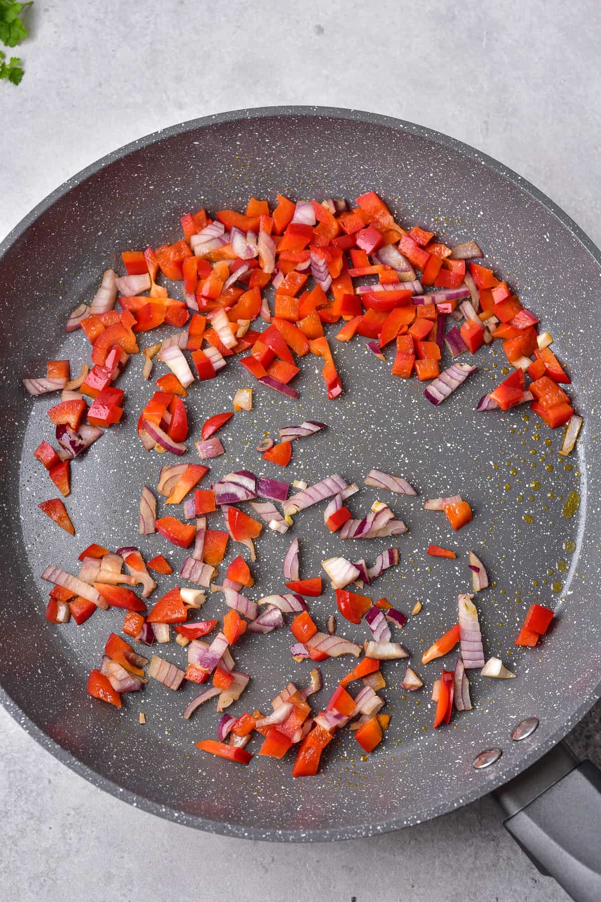 Red pepper and onions in a frying pan.