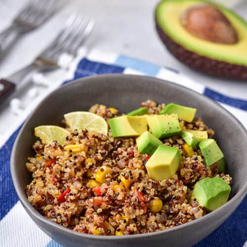 Mexican Quinoa made in one pot served in a gray bowl garnished with lime and avocado.