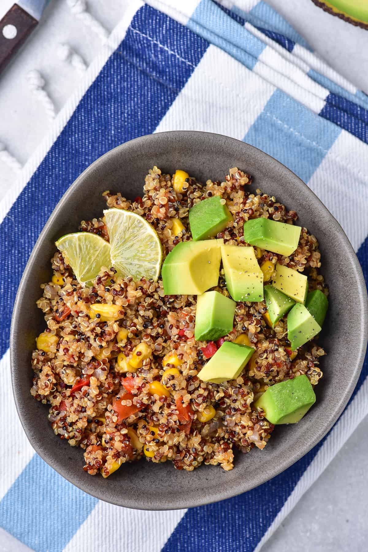 Mexican Quinoa made in one pot served in a gray bowl garnished with lime and avocado.