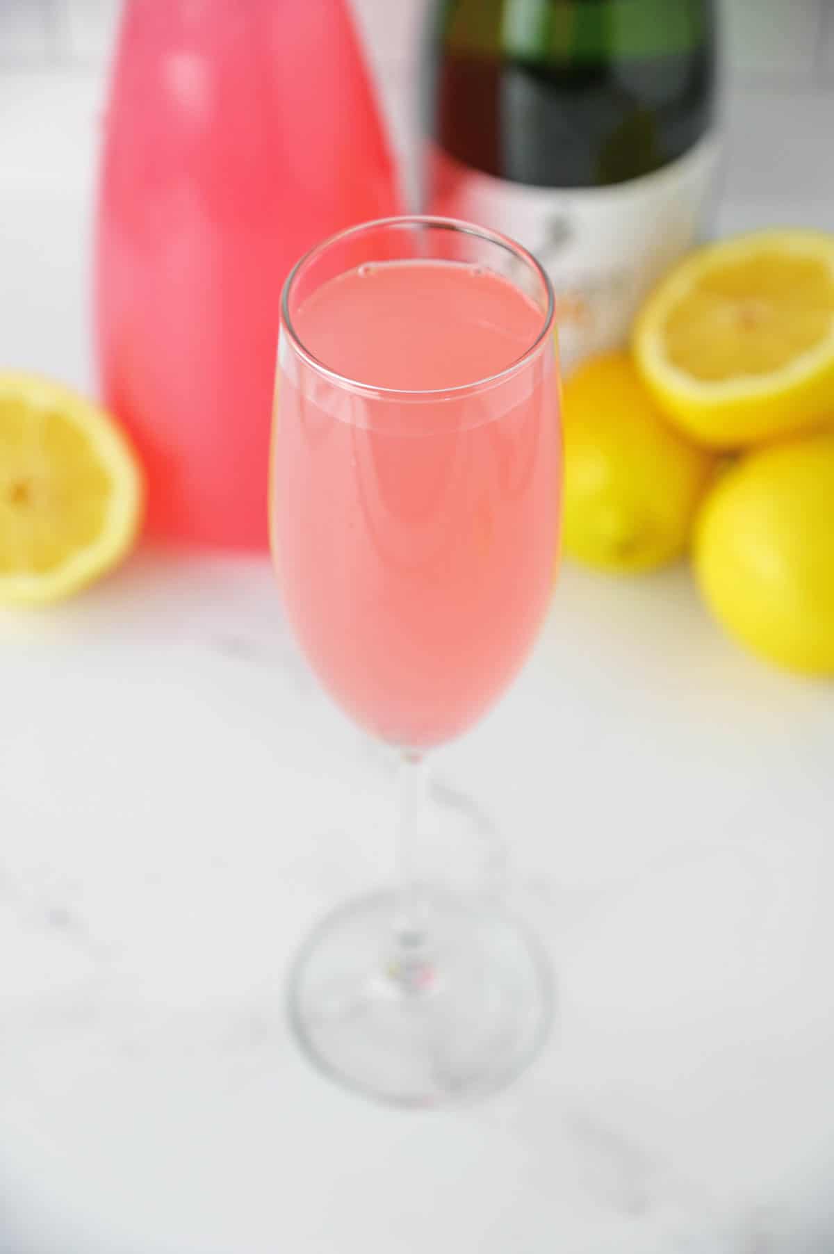 Pink Mimosa in a champagne flute with a lemon slice garnish.