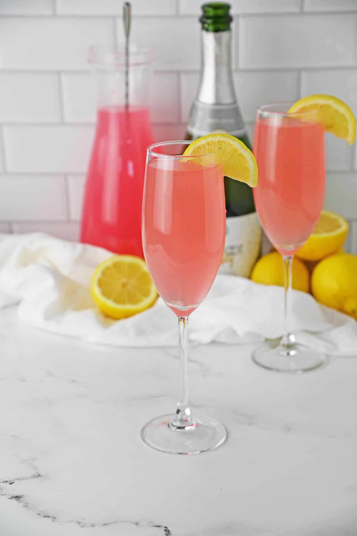 Pink Mimosa in a champagne flute with a lemon slice garnish.