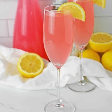 Pink Mimosa on a champagne flute with a lemon slice.