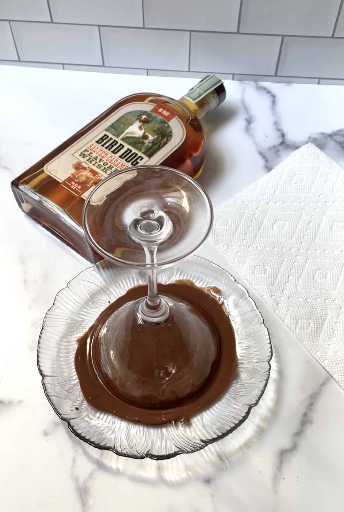 Martini glass upside down on plate of melted chocolate.