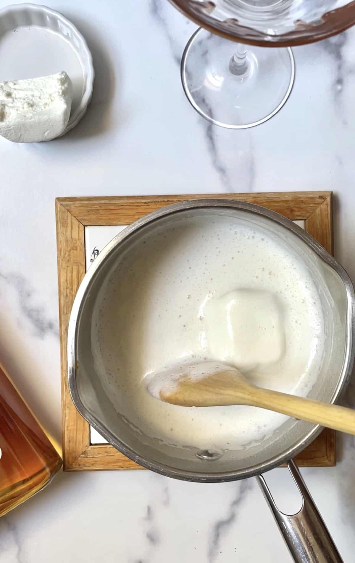 Melted marshmallow in pan with wooden spoon.