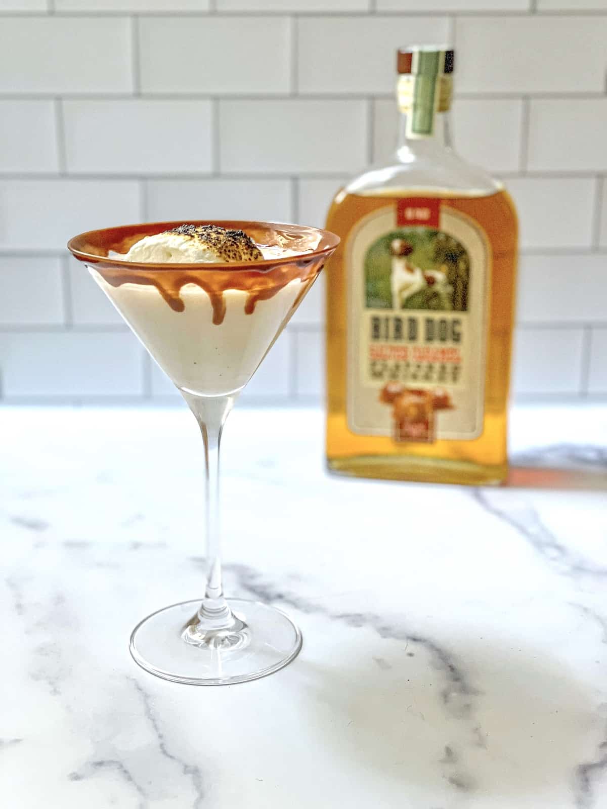 Bird Dog Whiskey bottle with cocktail in a martini glass topped with a marshmallow.
