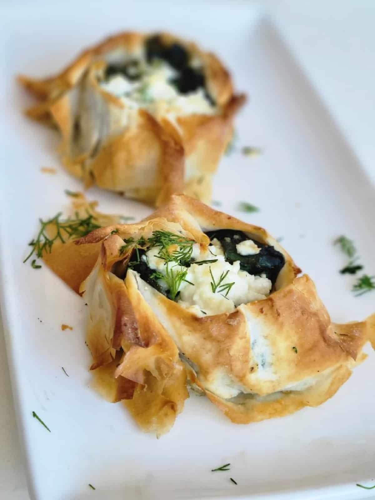 Spanakopita sprinkled with dill on a white plate.