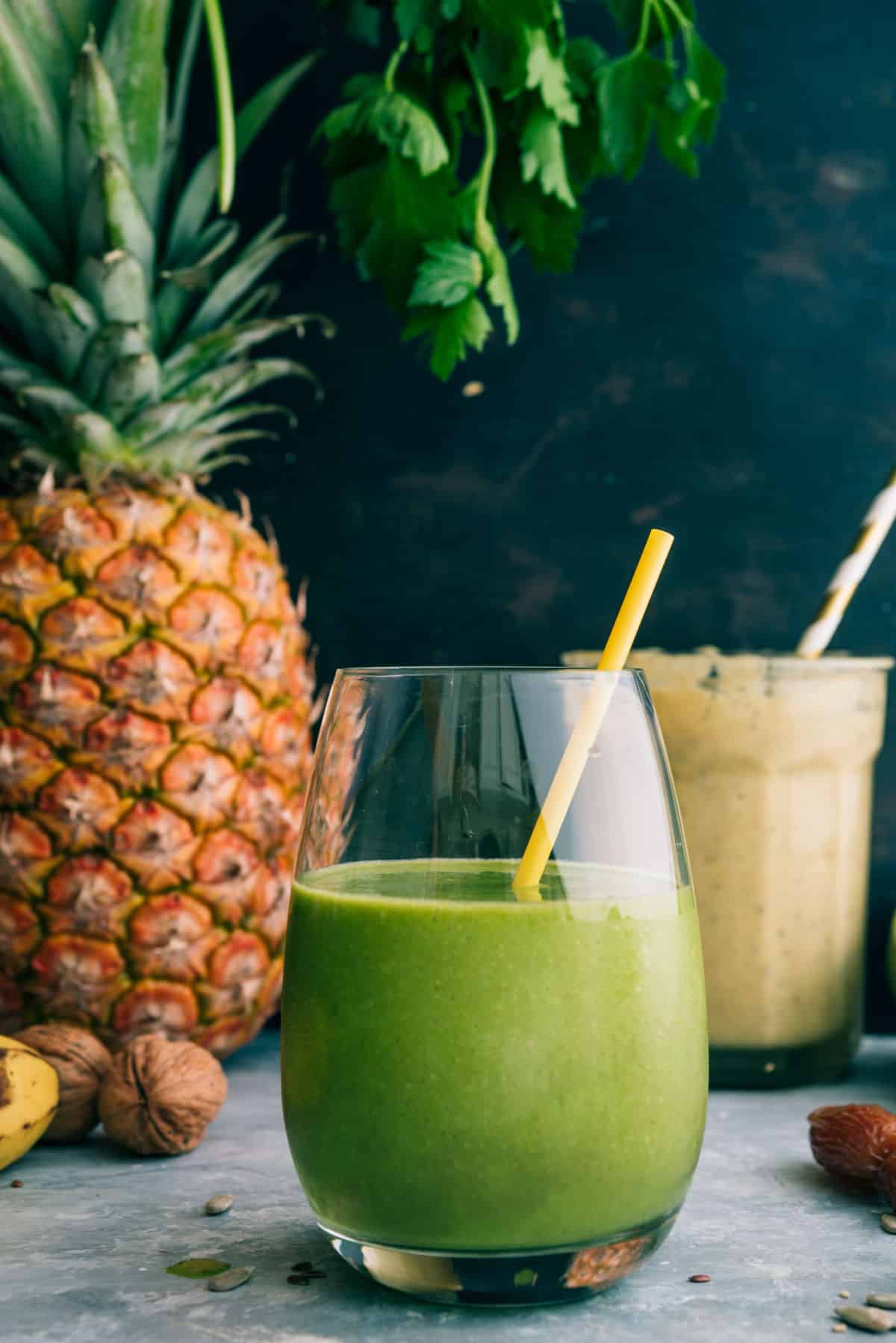 Avocado smoothie and pineapple banana smoothie with straws and pineapple.