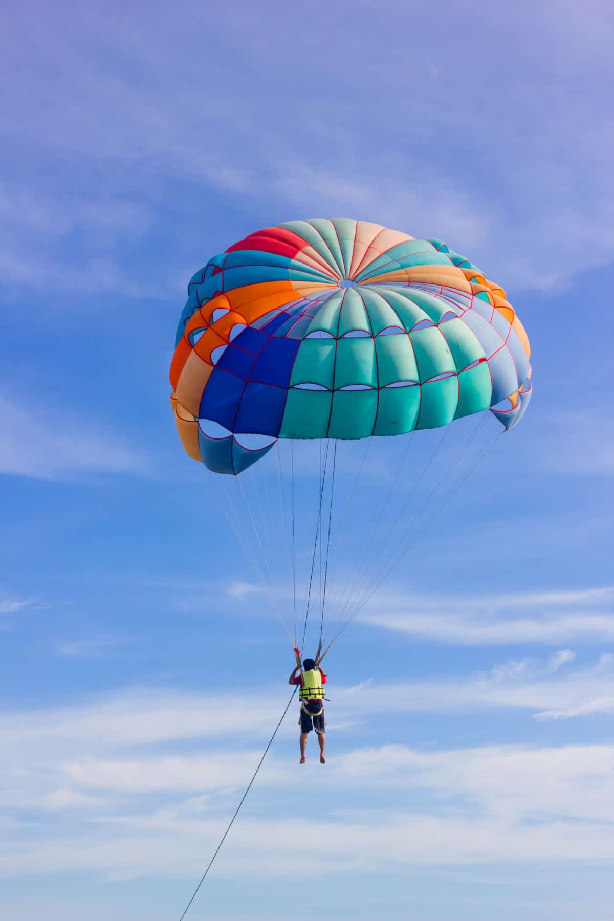 Person parasailing with blue sky.