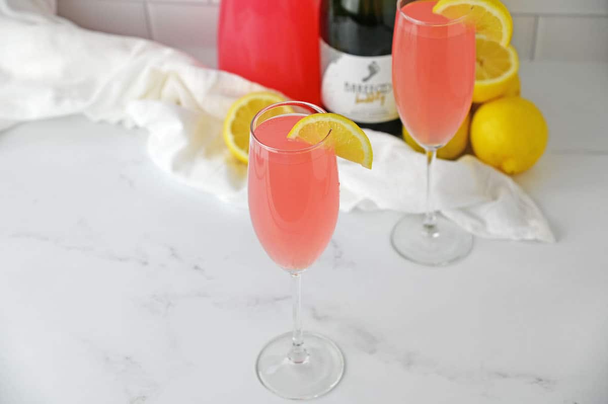 Pink Mimosa in a champagne flute with a lemon slice garnish.