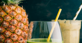 Smoothies in glasses with straws and pineapple.