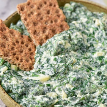 Spinach dip in a bowl with crackers.