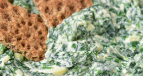 Spinach dip with crackers in bowl.