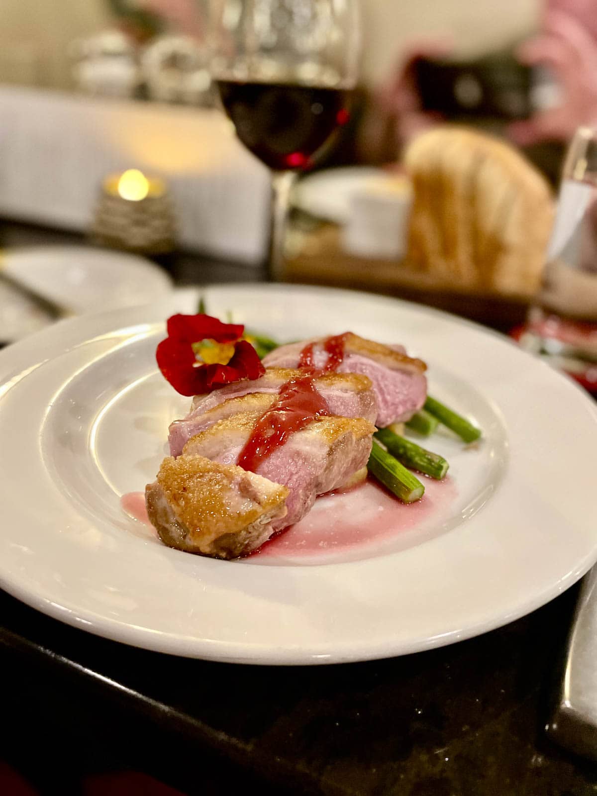 Duck with red sauce on plate with asparagus.