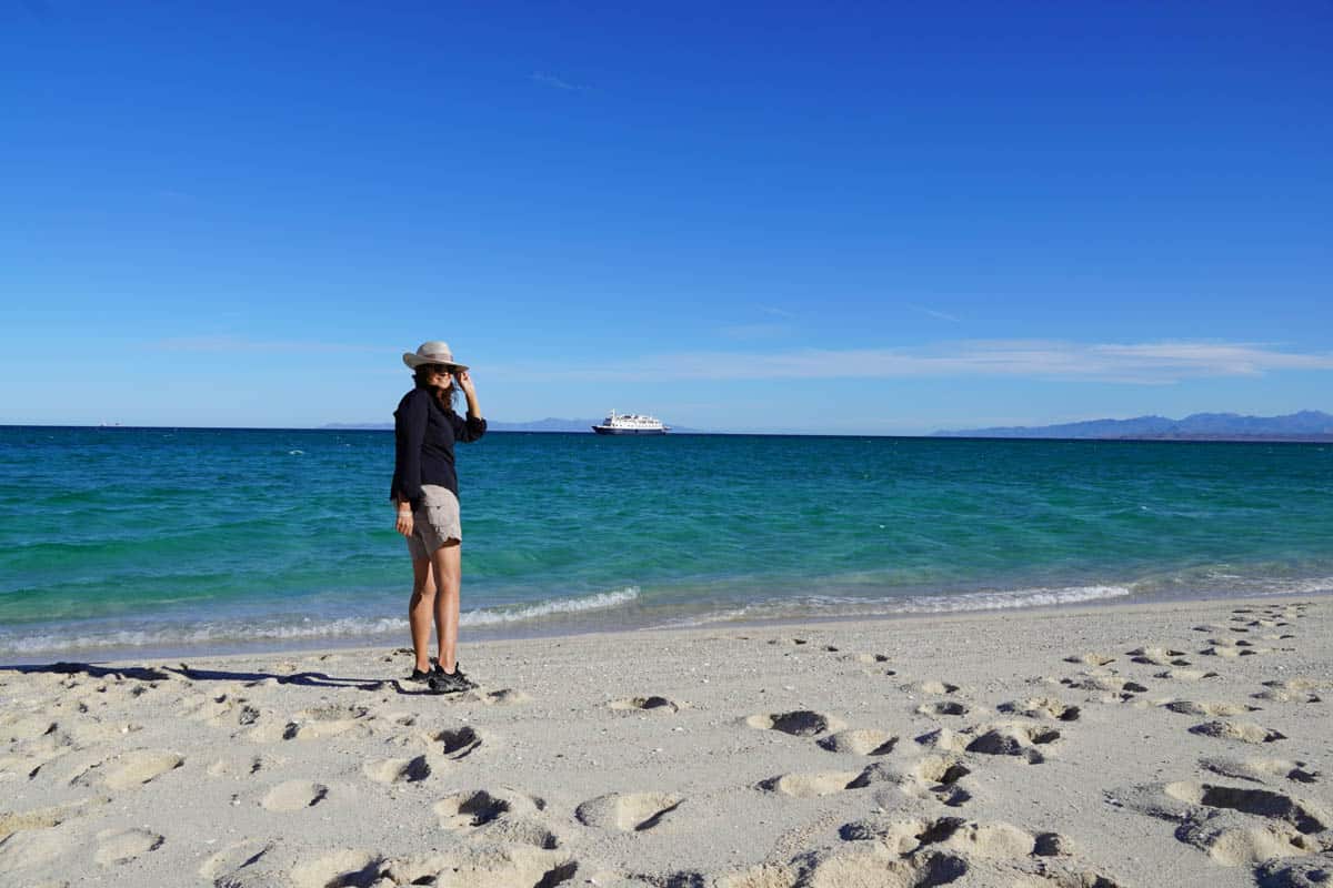 Woman standing on beach in Baja Mexico with ship in background.