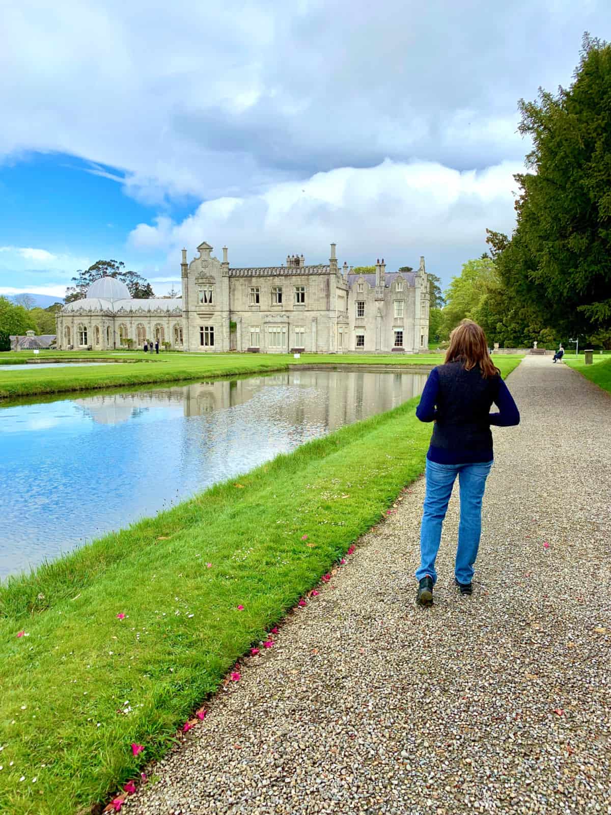 Woman walking next to a lake in front of a castle.