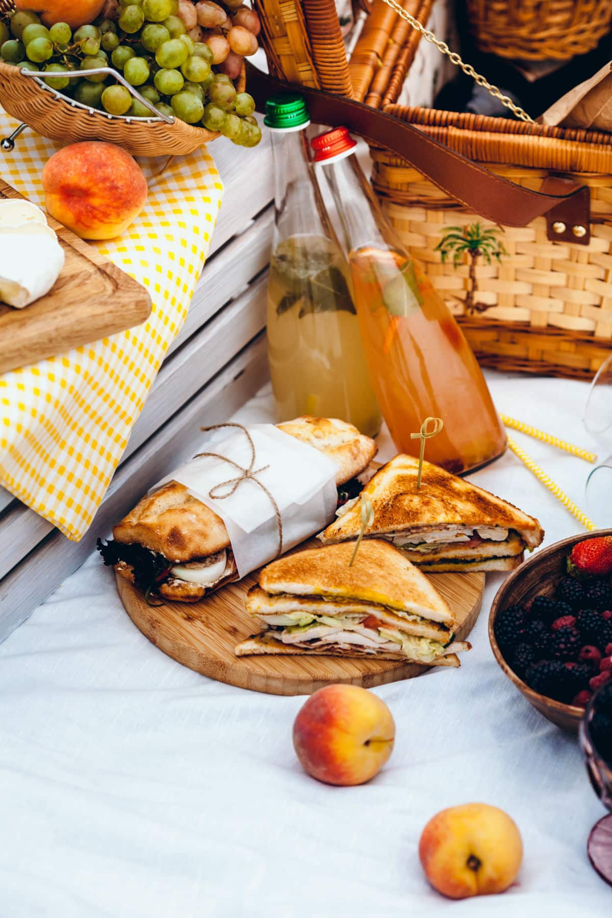 Drinks, sandwiches, and a basket to pack for a picnic.