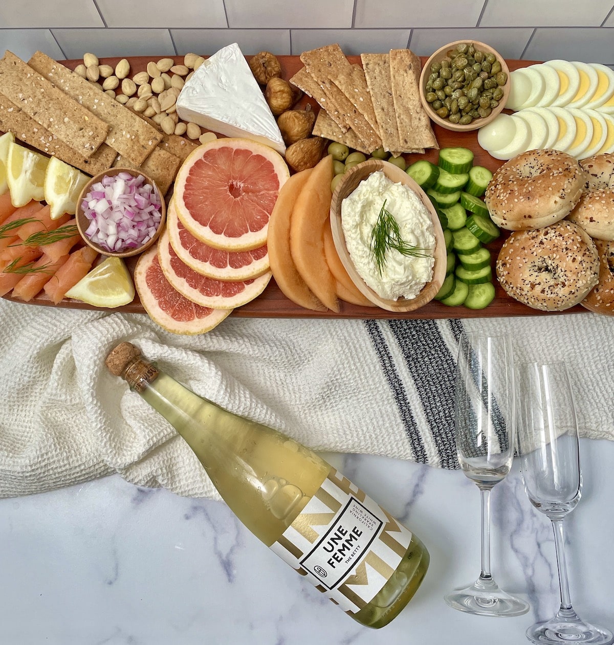 Breakfast board with a bottle of wine and glasses.