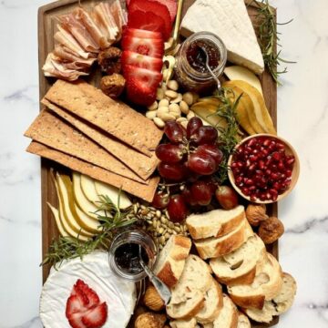 Brie charcuterie board with fruit, nuts, bread, and crackers.