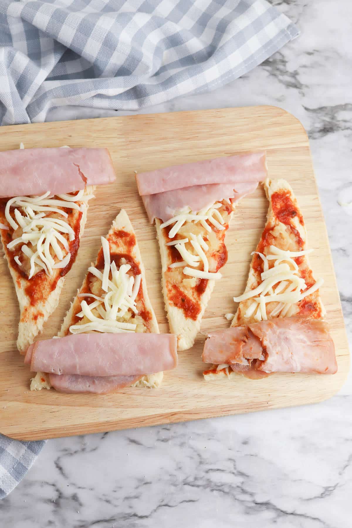 Crescent roll dough with pizza sauce, pineapple, cheese, and ham.