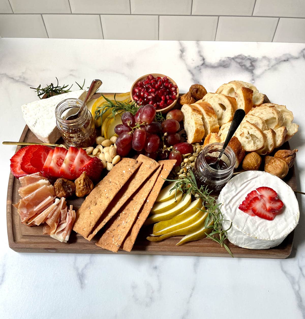 Brie charcuterie board with fruit, nuts, bread, and crackers.