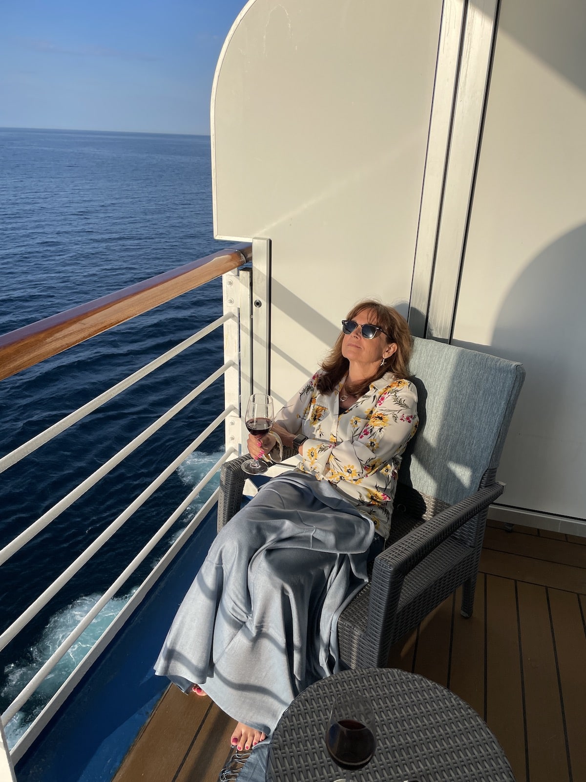 Woman in chair on cruise ship balcony.