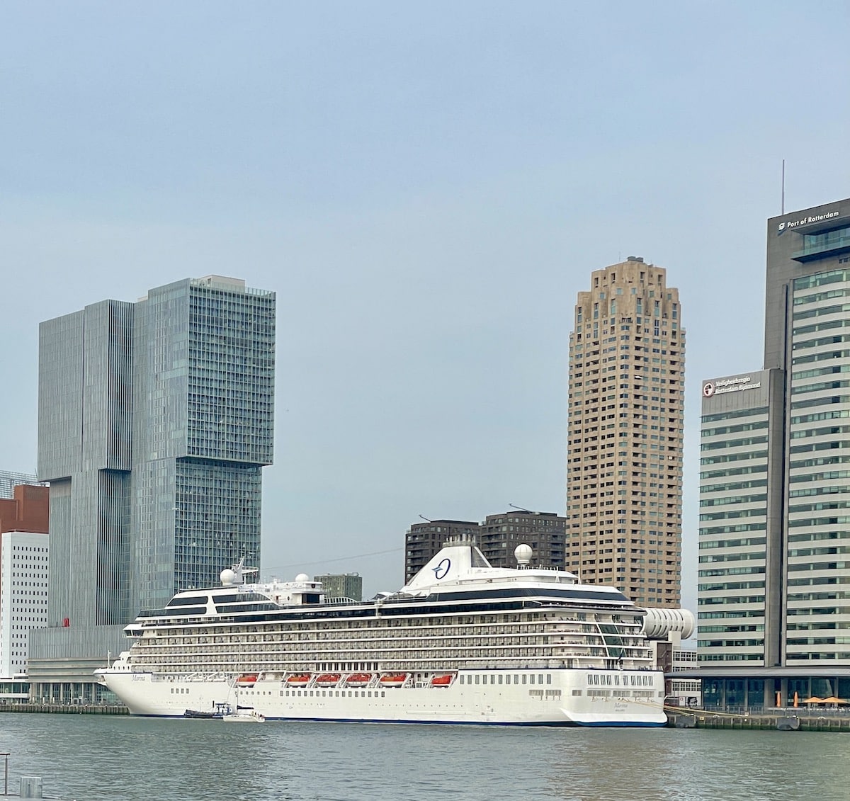 Oceania cruise ship docked in front of office buildings.