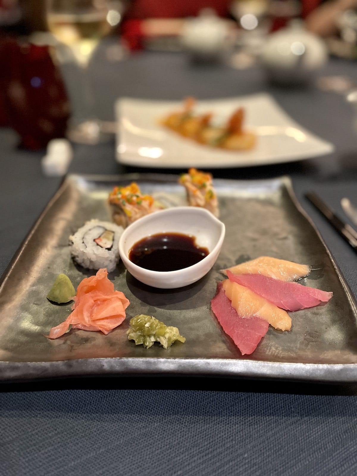 Sashimi and sushi with ginger and soy sauce on a plate.