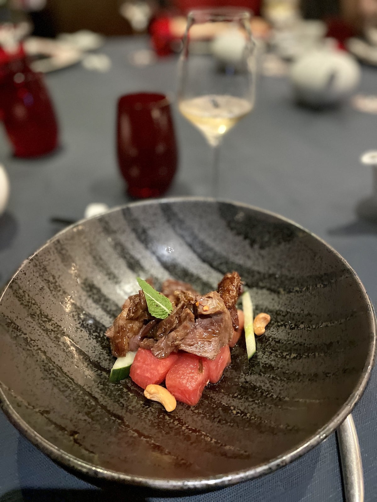 Seared duck and watermelon salad in grey bowl.