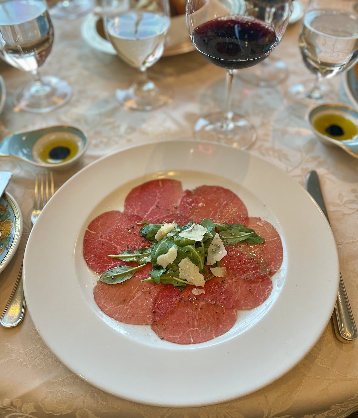 Beef carpaccio with rocket and slice parmesan salad on top.