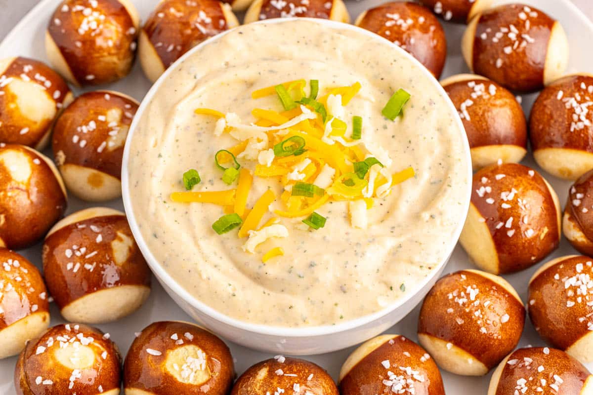 German beer cheese in a white bowl surrounded by pretzel bites.