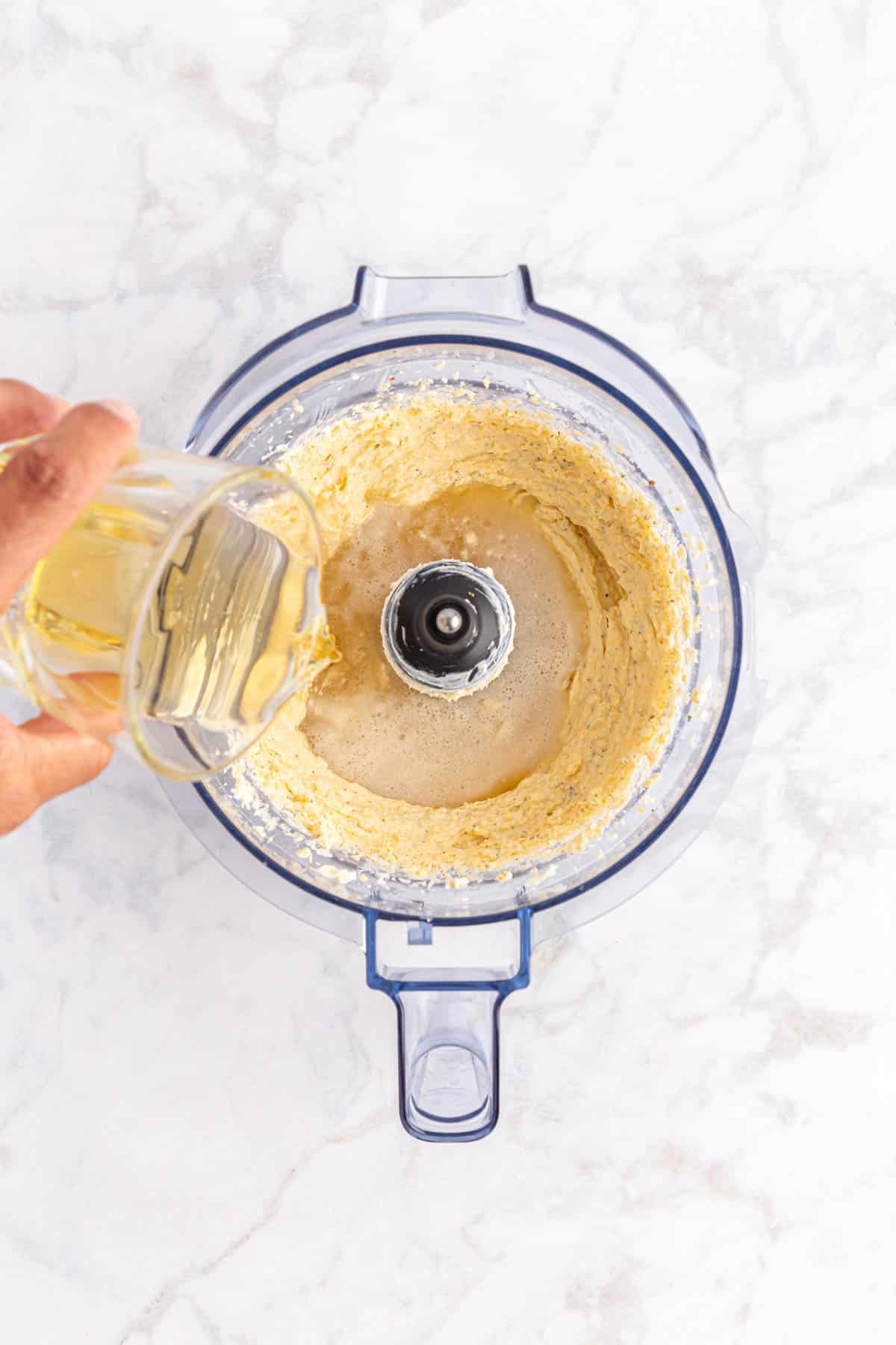 Adding beer to cheese dip in food processor.